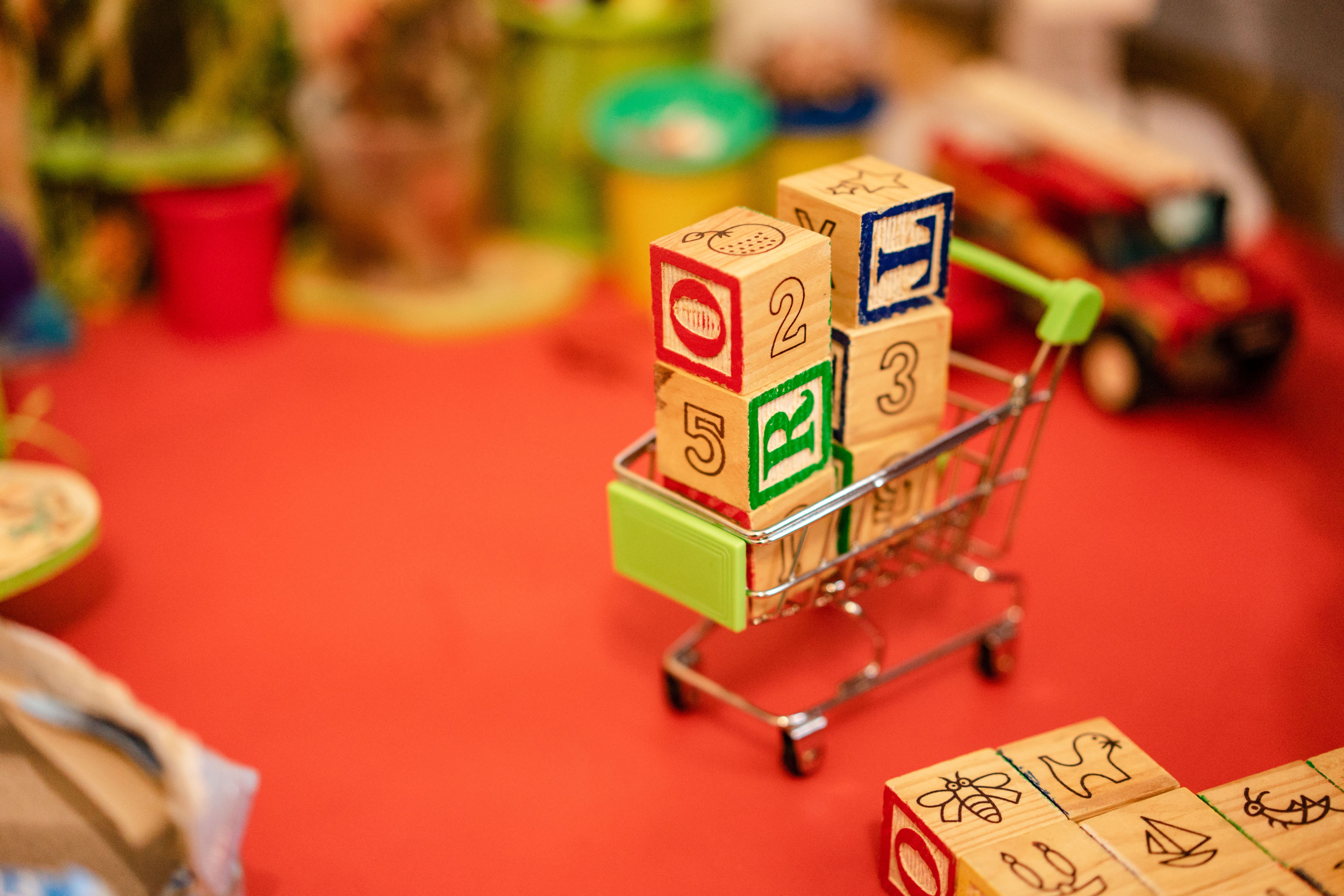 A small toy car sitting inside a supermarket shopping trolley.
