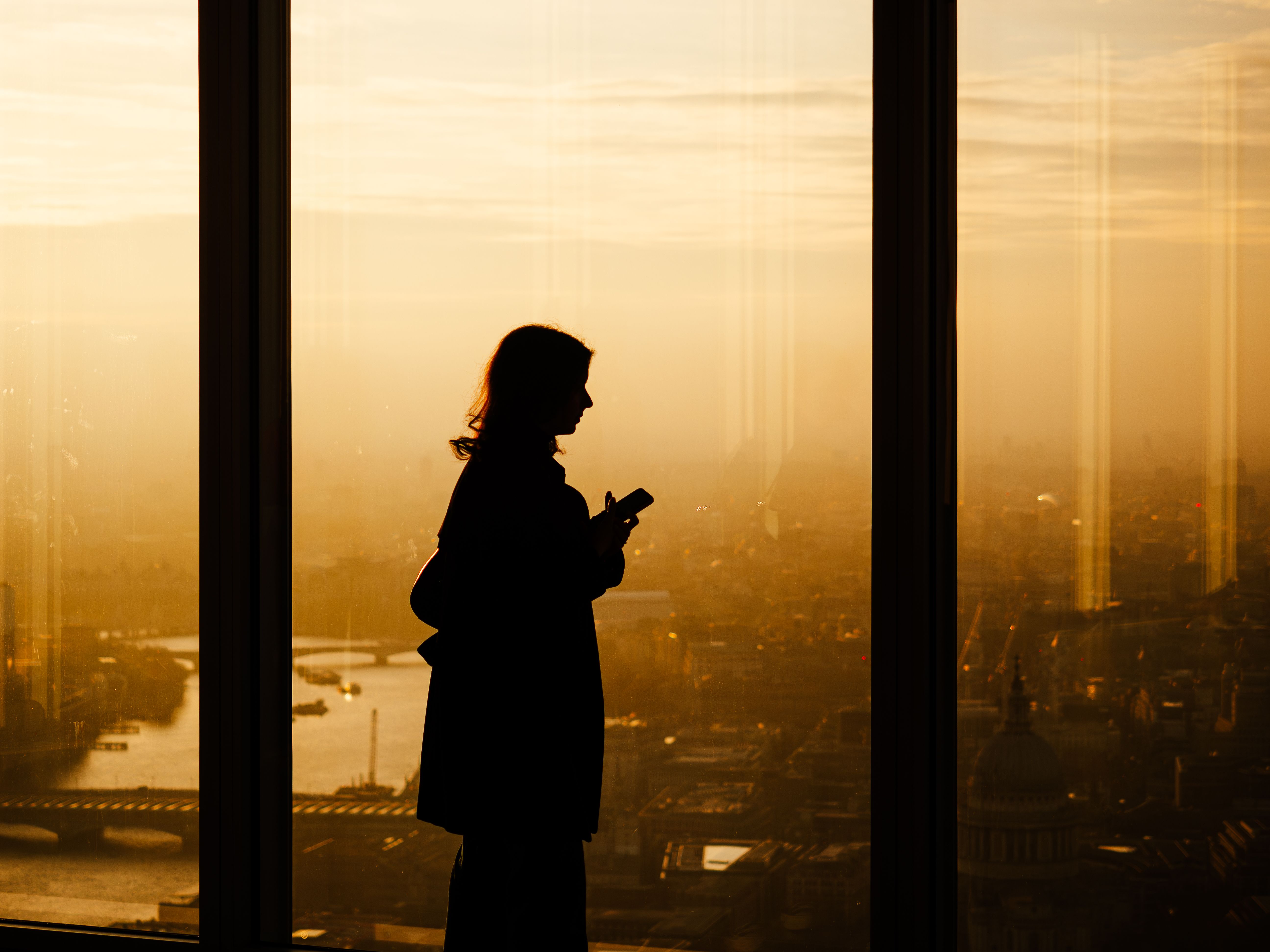Traveller using a smartphone beside an airport window.
