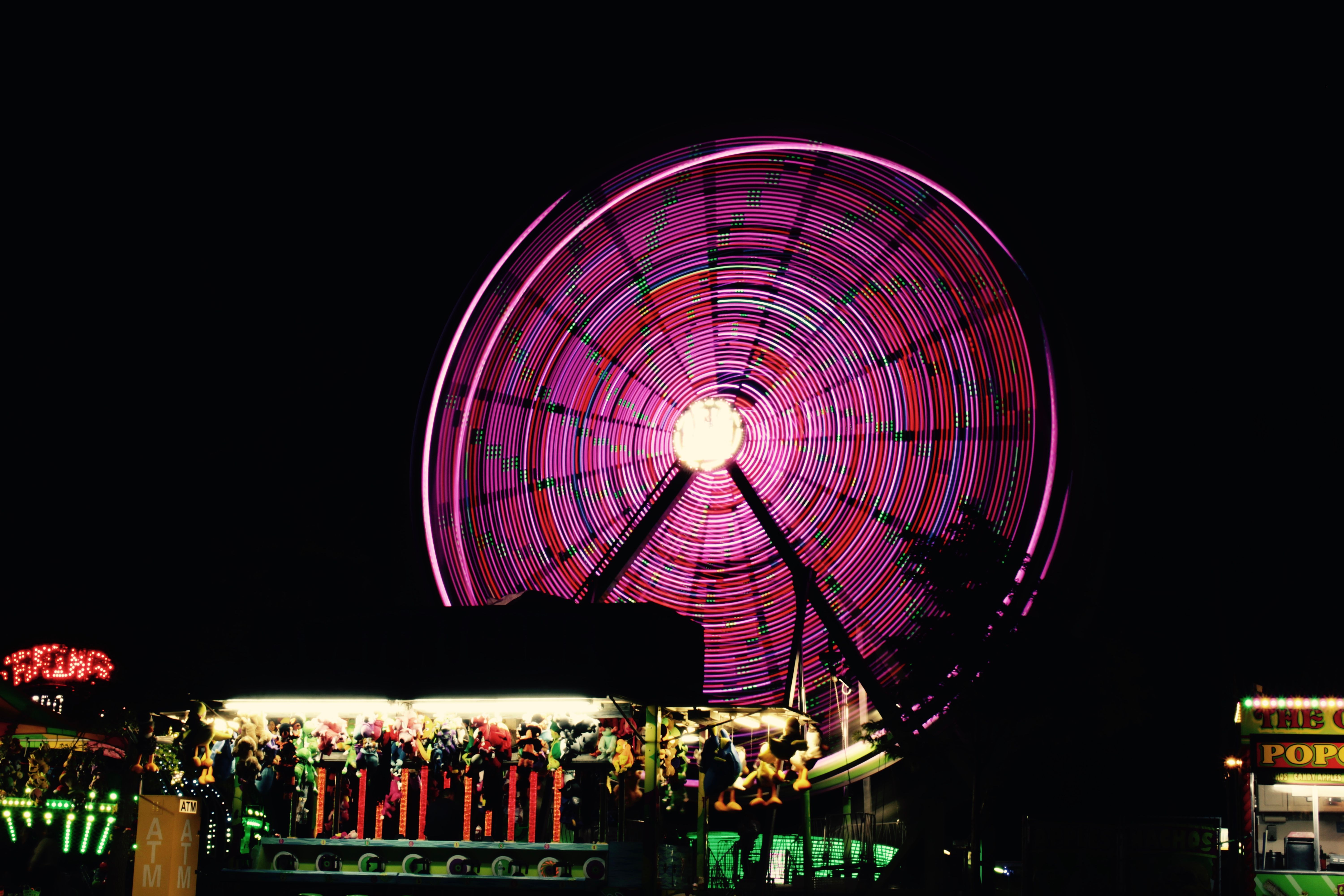 A carousel glowing purple at night, its lights blurred by motion.