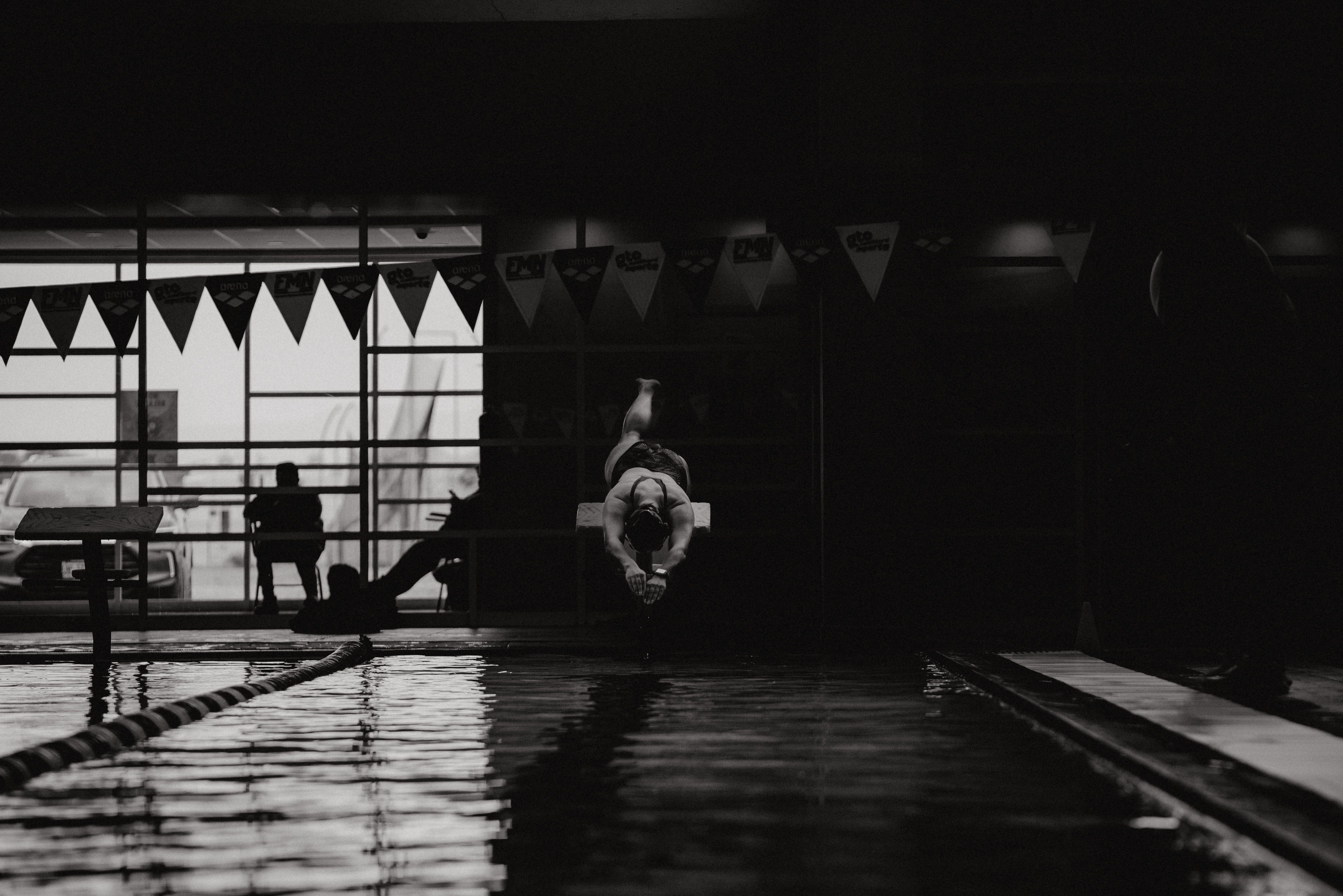 A woman standing on a diving board above a swimming pool.